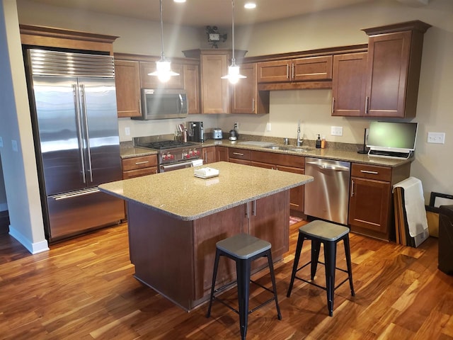 kitchen featuring a breakfast bar, sink, high quality appliances, a kitchen island, and pendant lighting