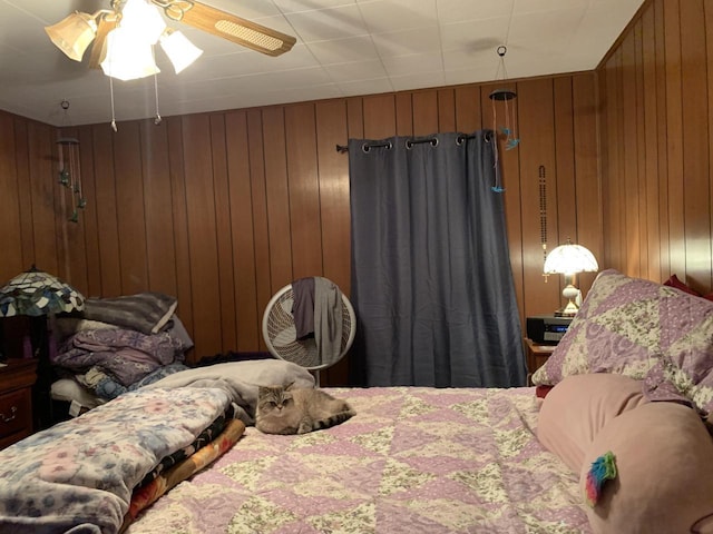 bedroom featuring ceiling fan and wooden walls