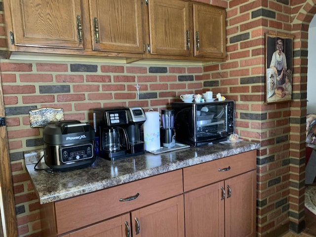 kitchen with brick wall and dark stone counters