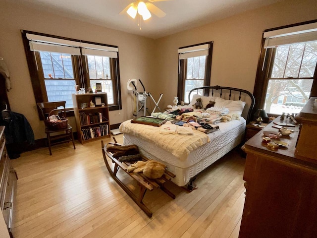 bedroom featuring multiple windows, ceiling fan, and light wood-type flooring