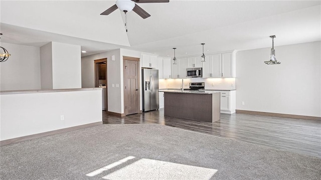 interior space featuring hanging light fixtures, appliances with stainless steel finishes, a center island, and white cabinets