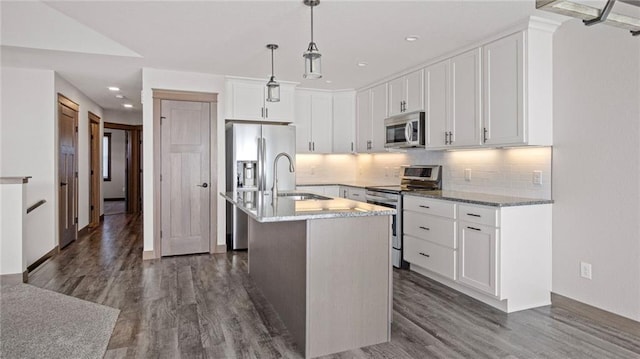 kitchen with appliances with stainless steel finishes, decorative light fixtures, white cabinetry, sink, and a kitchen island with sink