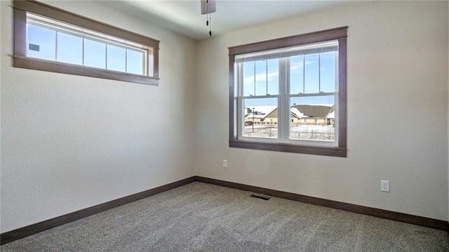 spare room with plenty of natural light, ceiling fan, and carpet flooring