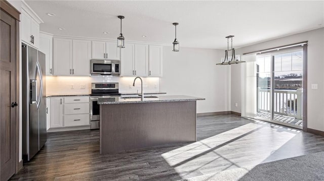 kitchen featuring white cabinetry, appliances with stainless steel finishes, decorative light fixtures, and a center island with sink