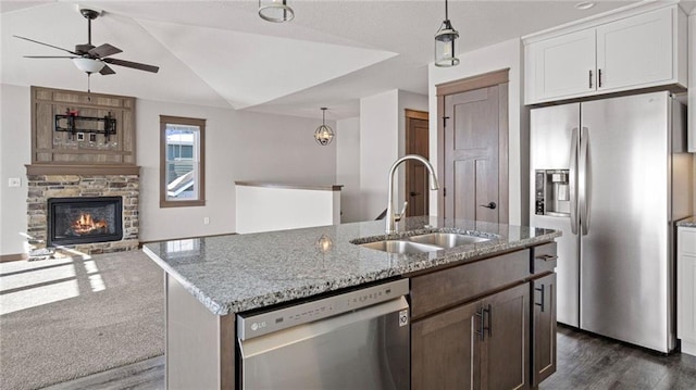 kitchen featuring appliances with stainless steel finishes, a stone fireplace, pendant lighting, sink, and white cabinets