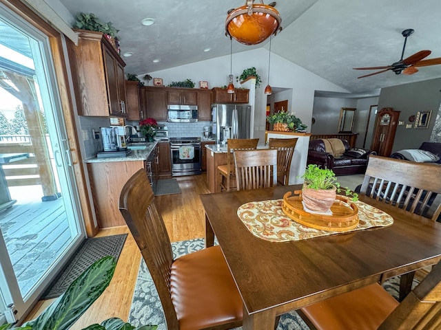 dining area featuring wood-type flooring, lofted ceiling, sink, and ceiling fan