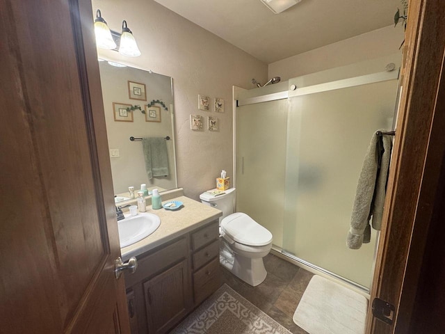 bathroom with vanity, a shower with door, and toilet