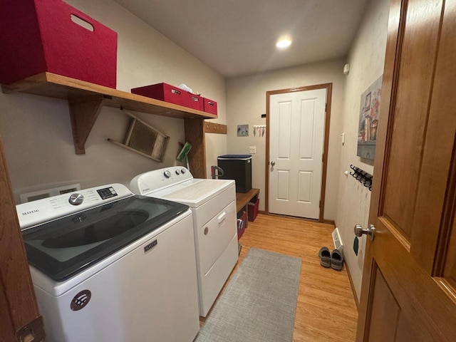 laundry area with light hardwood / wood-style flooring and washing machine and dryer