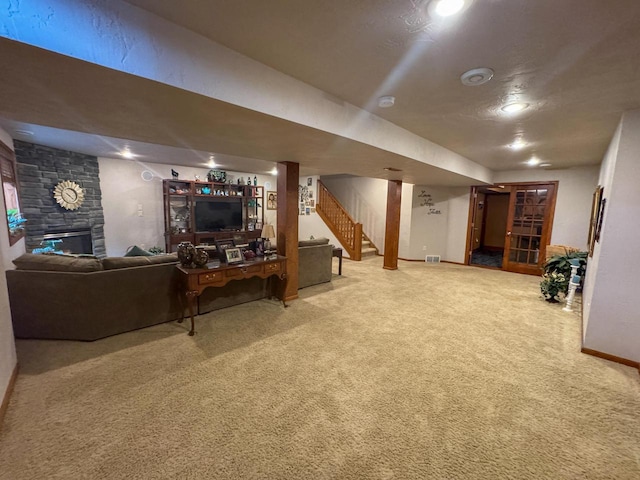 carpeted living room featuring a stone fireplace