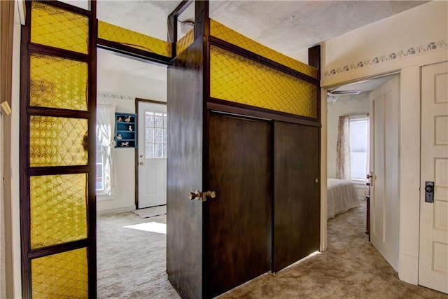 hallway with a wealth of natural light and light colored carpet