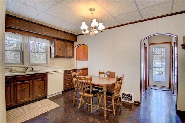 dining area featuring a drop ceiling, sink, plenty of natural light, and a chandelier