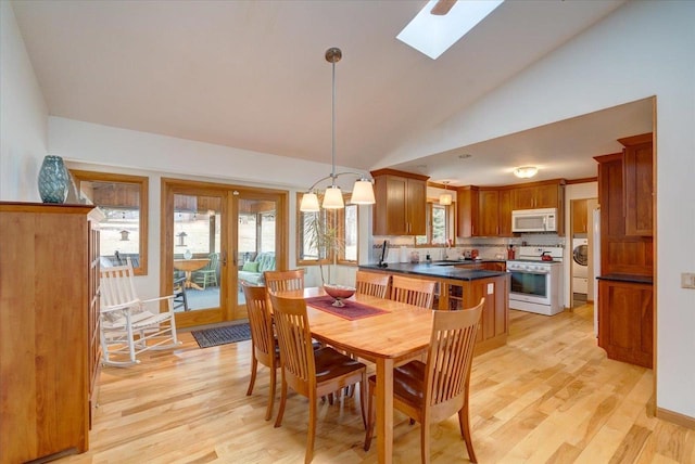 dining space with high vaulted ceiling, sink, light wood-type flooring, and a skylight