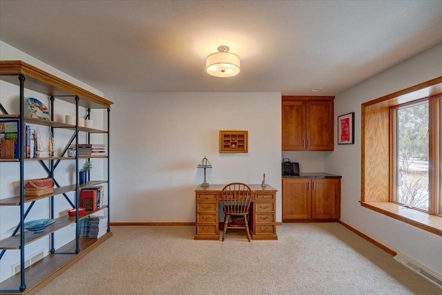 home office featuring light carpet and built in desk