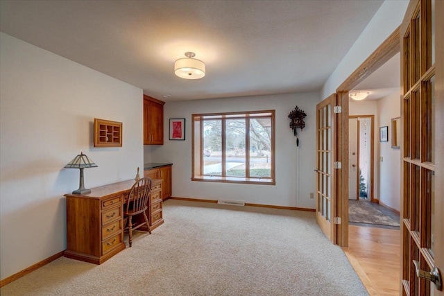 office area with built in desk, light colored carpet, and french doors