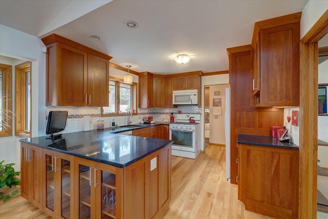 kitchen with tasteful backsplash, sink, white appliances, and light hardwood / wood-style floors