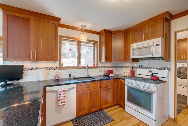 kitchen featuring sink, white appliances, hanging light fixtures, backsplash, and washer / dryer