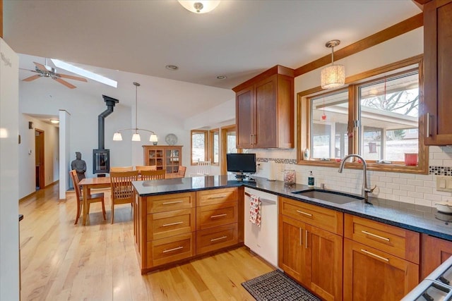 kitchen with pendant lighting, dishwasher, sink, light hardwood / wood-style floors, and kitchen peninsula