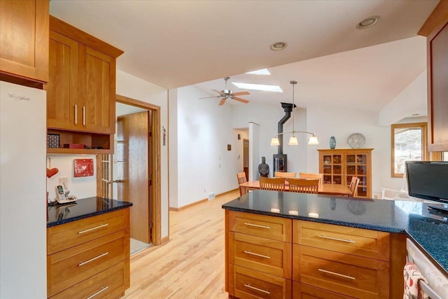 kitchen with decorative light fixtures, light wood-type flooring, white refrigerator, ceiling fan, and vaulted ceiling with skylight