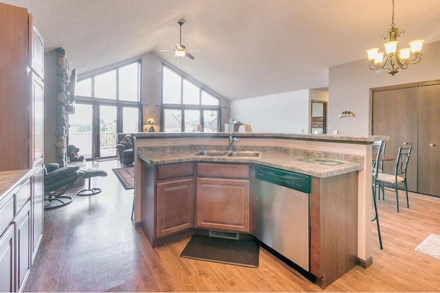 kitchen featuring decorative light fixtures, dishwasher, an island with sink, sink, and a breakfast bar area