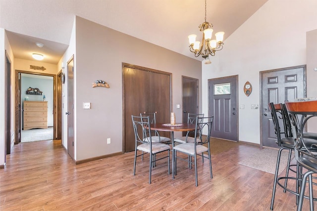 dining room with a notable chandelier, high vaulted ceiling, and light wood-type flooring