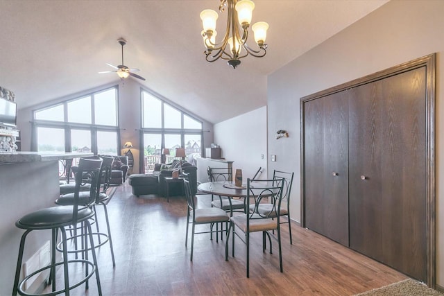 dining space with hardwood / wood-style flooring, high vaulted ceiling, and ceiling fan with notable chandelier