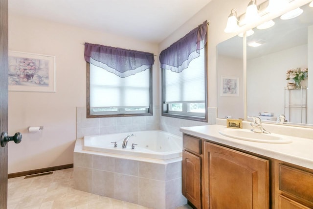 bathroom featuring tile patterned flooring, vanity, and tiled bath