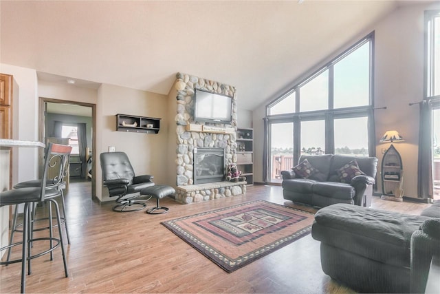 living room featuring wood-type flooring, a fireplace, and high vaulted ceiling