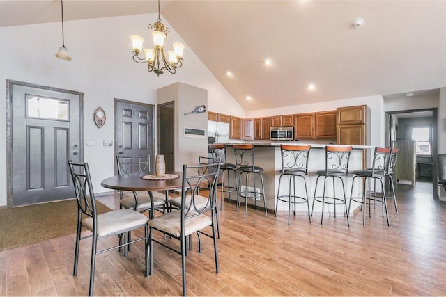 dining area featuring high vaulted ceiling, light hardwood / wood-style floors, and a chandelier