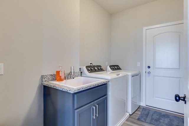 laundry room featuring light hardwood / wood-style floors, sink, cabinets, and washer and dryer