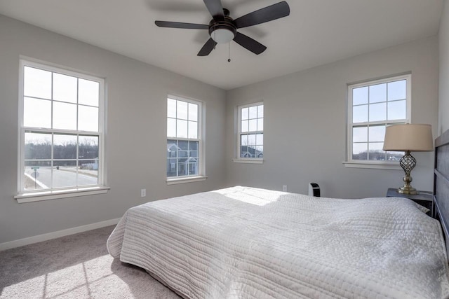 bedroom featuring multiple windows, light colored carpet, and ceiling fan