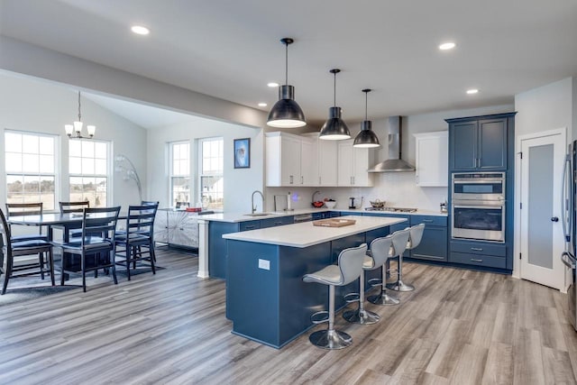 kitchen featuring decorative light fixtures, kitchen peninsula, wall chimney exhaust hood, and a kitchen bar