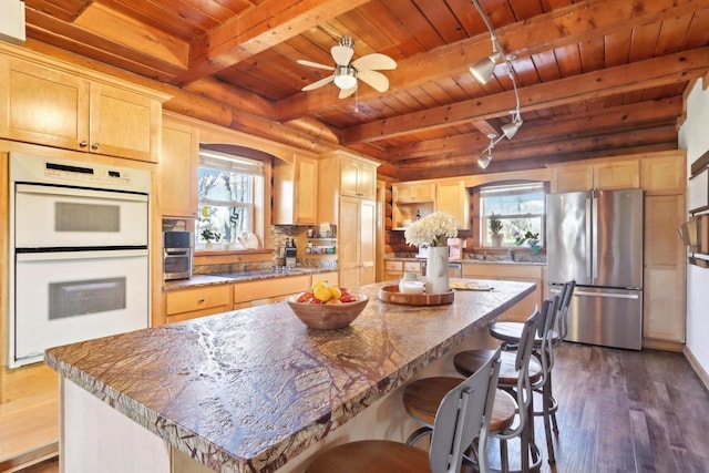 kitchen featuring a center island, wooden ceiling, stainless steel refrigerator, light brown cabinets, and double oven