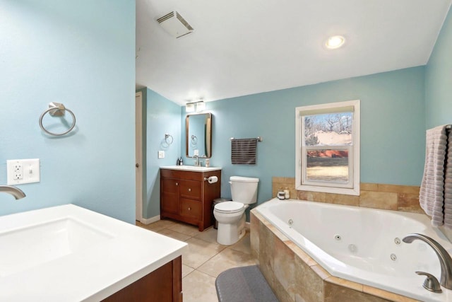 bathroom featuring tiled tub, vanity, tile patterned flooring, and toilet