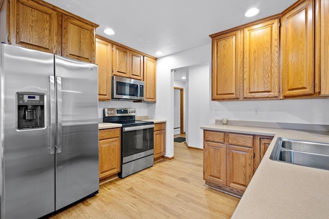 kitchen featuring appliances with stainless steel finishes, sink, and light hardwood / wood-style floors