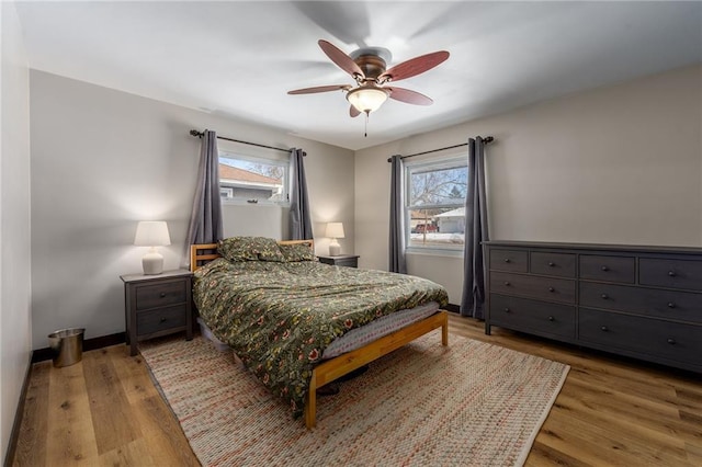 bedroom with multiple windows, ceiling fan, and light wood-type flooring