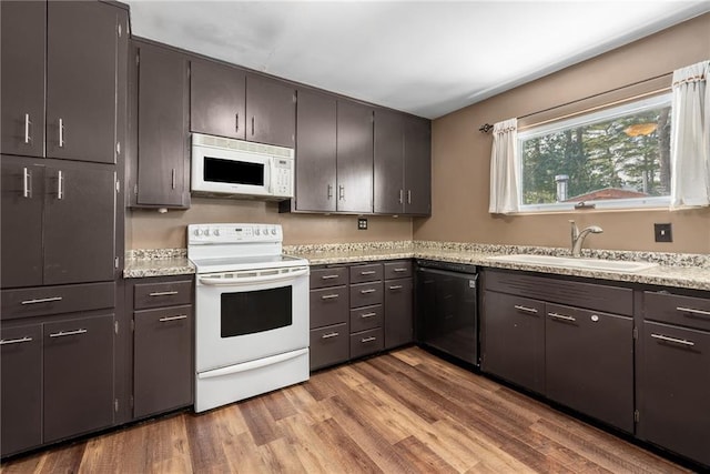 kitchen with dark brown cabinets, sink, white appliances, and light hardwood / wood-style flooring