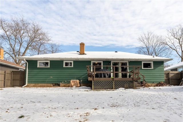 snow covered back of property with a deck