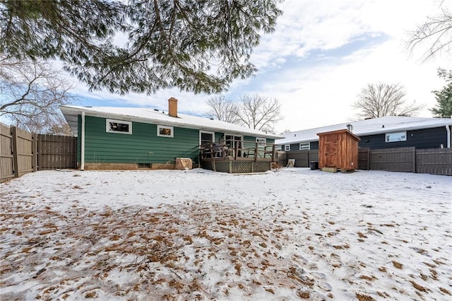 snow covered house featuring a wooden deck and a storage shed