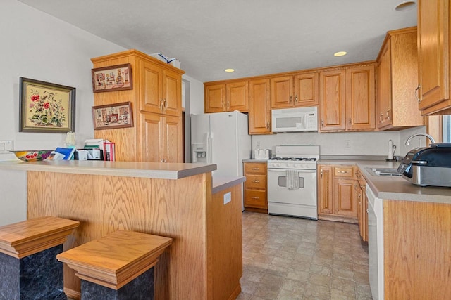 kitchen with sink, white appliances, a kitchen breakfast bar, and kitchen peninsula