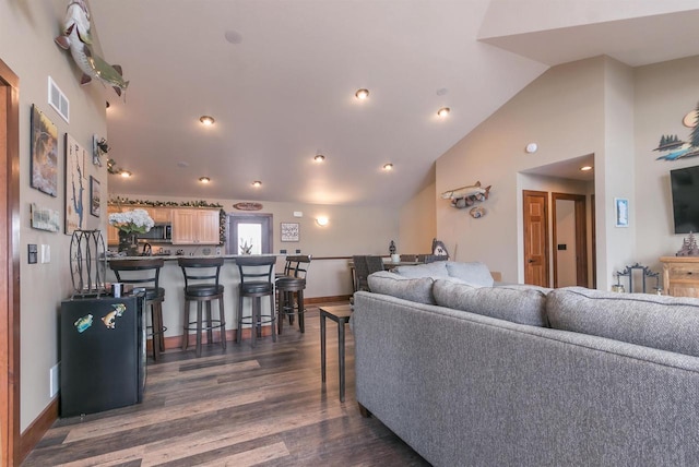 living room with indoor bar, dark hardwood / wood-style floors, and high vaulted ceiling