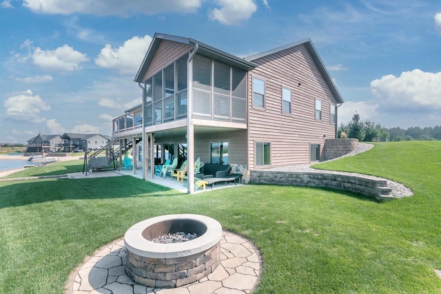 back of property with an outdoor living space with a fire pit, a patio, a sunroom, and a lawn