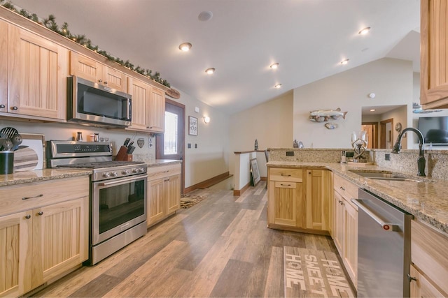 kitchen featuring light brown cabinetry, sink, stainless steel appliances, and kitchen peninsula