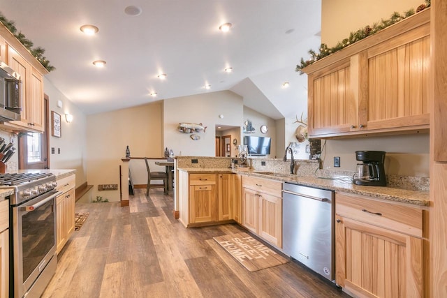 kitchen with appliances with stainless steel finishes, sink, light brown cabinets, and kitchen peninsula