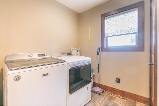 laundry area with independent washer and dryer and light hardwood / wood-style flooring