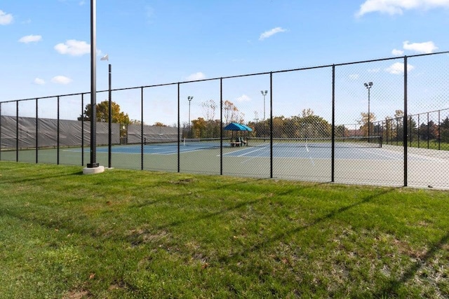 view of tennis court featuring a yard