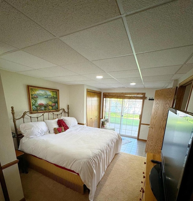 bedroom featuring a paneled ceiling, tile patterned flooring, and access to outside