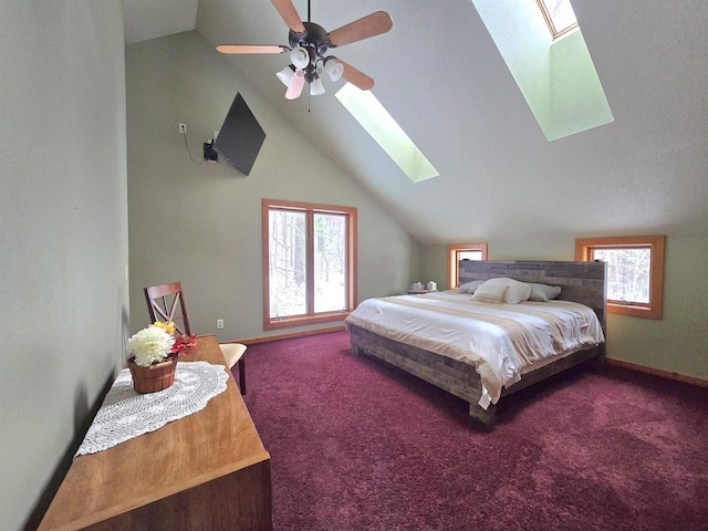 carpeted bedroom with multiple windows, vaulted ceiling with skylight, and ceiling fan