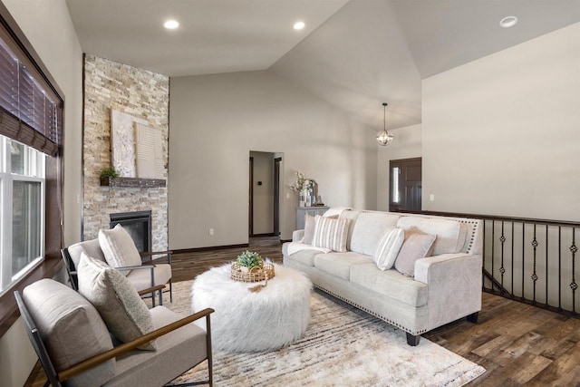 living room featuring high vaulted ceiling, dark hardwood / wood-style floors, an inviting chandelier, and a fireplace