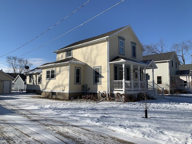 snow covered house featuring a porch