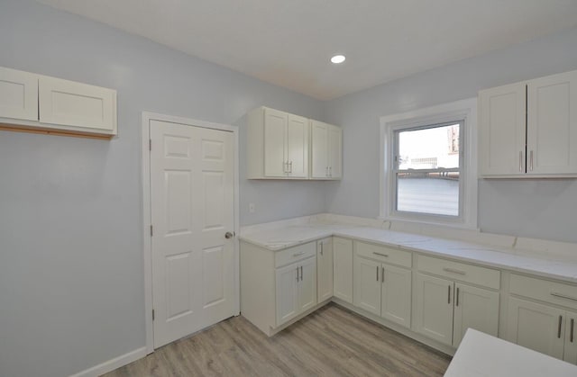 kitchen with white cabinetry, light hardwood / wood-style floors, and light stone counters